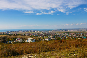 Aerial panorama of city-resort Anapa, Russia. Summer day under a blue cloudy sky. The view from the mountains. New buildings and the waters of the Black sea.