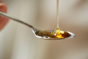 close up of honey pouring to teaspoon - obrazy, fototapety, plakaty