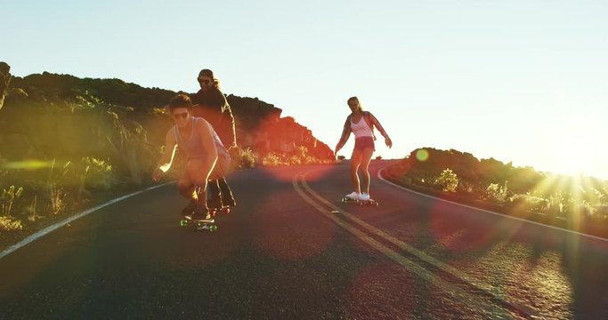 Friends skateboarding riding down mountain road