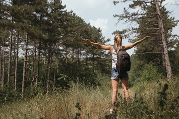 Portrait of female backpacker with outstretched arms enjoying forest landscape and sport achievement. Motivation and inspiration concept. 