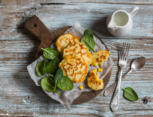 Gluten free corn fritters and fresh spinach on a wooden board, top view.