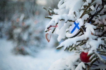 Finland Christmas holiday greetings card. Christmas tree covered with snow and a Finnish flag. Winter outdoor scene background - 126534327