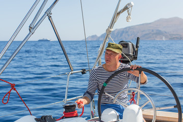 Fototapeta premium Man drives sailing yacht at the sea. Luxery boats.