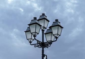 Fototapeta na wymiar Old big street lamppost with cloudy sky