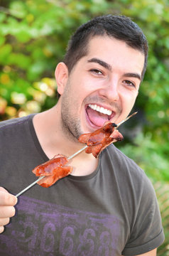 handsome young man  eating sausages outdoor