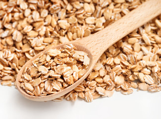 Close up of oat flakes in wooden spoon on white background. Healthy food. Top view, high resolution product