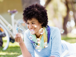 Obraz premium Beautiful woman blowing bubbles in park