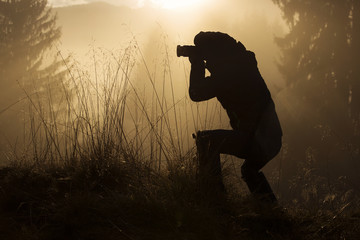 Silhouette of photographer at sunrise in the forest