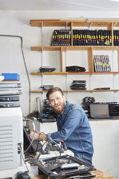 Worker in computer recycling plant working on laptop