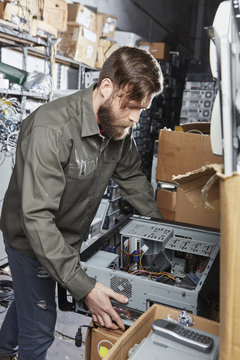 Worker in computer recycling plant carrying pc casing