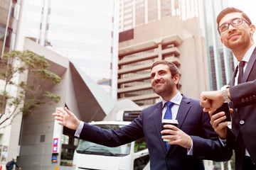 Two young businessmen hailing for a taxi