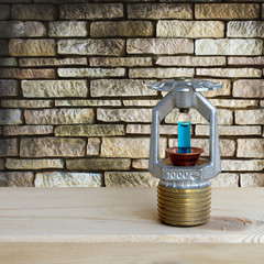 fire sprinkler with fire on wooden and stone wall background.