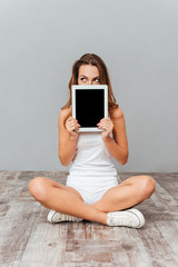 Portrait of a woman covering her face with tablet computer