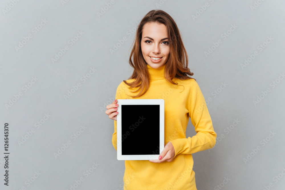 Wall mural Woman in yellow sweater showing tablet computer with blank screen