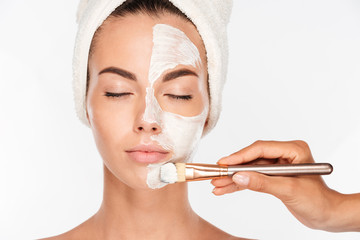 Woman getting beauty skin mask treatment on face with brush