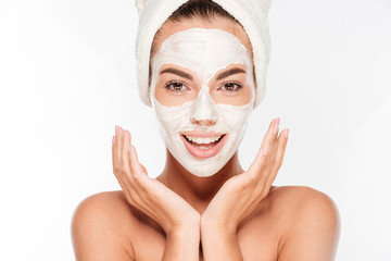 Beautiful smiling woman with white clay facial mask on face