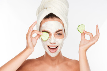Woman with facial mask and cucumber slices in her hands