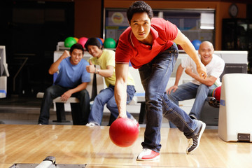 Fototapeta na wymiar Man bowling, friends cheering in the background