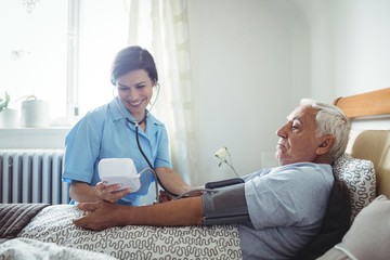 Nurse checking blood pressure of senior man