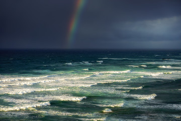 waves in rough sea with stormy clouds and rainbow