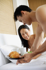Obraz na płótnie Canvas Woman in bed, man bringing breakfast tray