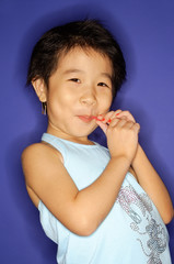 Young girl sucking on lollypop, smiling