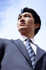 Businessman standing, looking away, low angle view