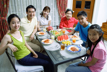 Three generation family around dining table, smiling at camera