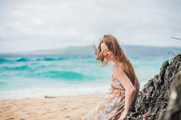 Fototapeta na wymiar A girl sits on a rock on the beach of Boracay