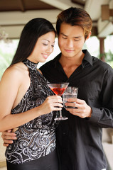 Well dressed couple, holding drinks, toasting