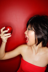 Woman in red tube tope holding red apple, mouth open