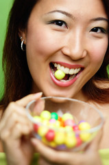 Woman biting candy and holding candy bowl