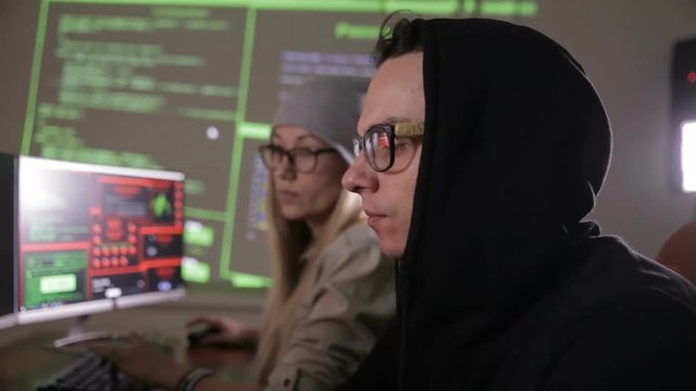 Young man and woman hackers trying to gain access to a computer system. HD.
