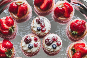 Delicious cupcakes with fresh strawberries, raspberries and blue