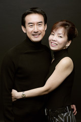 Couple standing side by side, woman with arm around mans waist