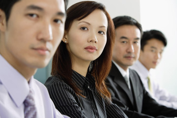 Business people in a row, looking at camera, head shot