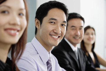 Business people in a row, smiling at camera
