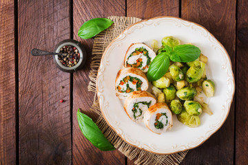 Chicken rolls with greens, garnished with stewed Brussels sprouts, apples and leeks on plate. Top view