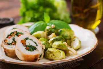Chicken rolls with greens, garnished with stewed Brussels sprouts, apples and leeks on plate.