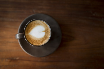 Hot latte art with  black glass on wooden table