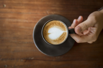 Hot latte art with  black glass on wooden table