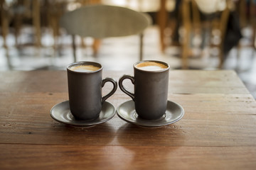Hot latte art with  black glass on wooden table