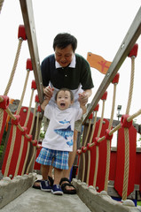 Father with young son in playground, walking on bridge
