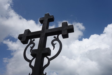 Sign of faith. Iron cross in a cloudy sky.