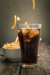 Cola with ice cubes Placed on wood table with French fries backg