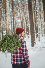 man in shirt carries the tree branches in the woods