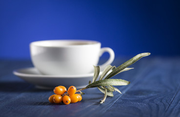 ripe sea buckthorn berries next to a cup with tea