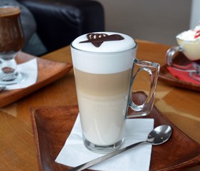 Latte Macchiato In Glass Cup On A Wooden Table    