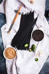 Fototapeta na wymiar Black Pasta Over White Linen Napkin. Ingredients For Asian Noodles. Top View
