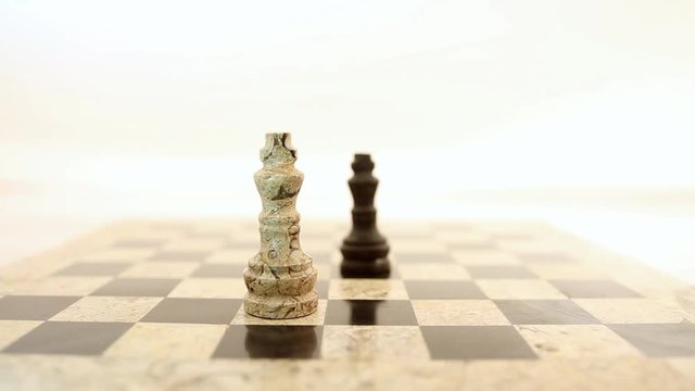 A black king standing in the midle of a chess board and a person puts a white king in front of the black king